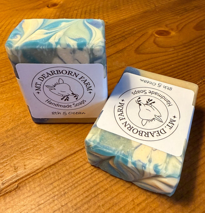 Two goat milk soap bars with 'Mt Dearborn Farm branding on a wooden surface